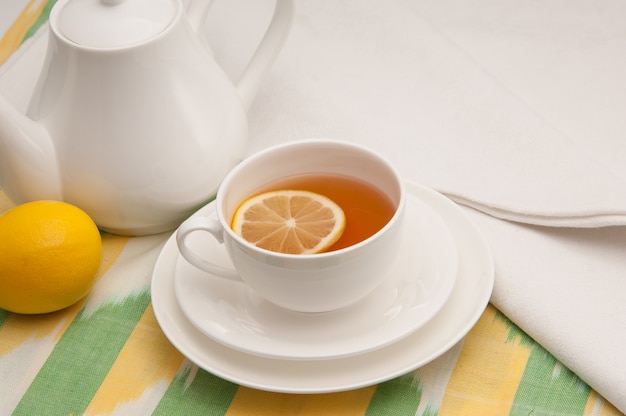 On a napkin cup of tea with lemon in a saucer and teapot