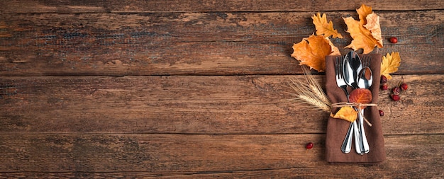 Napkin cutlery and autumn leaves on a wooden background with space to copy