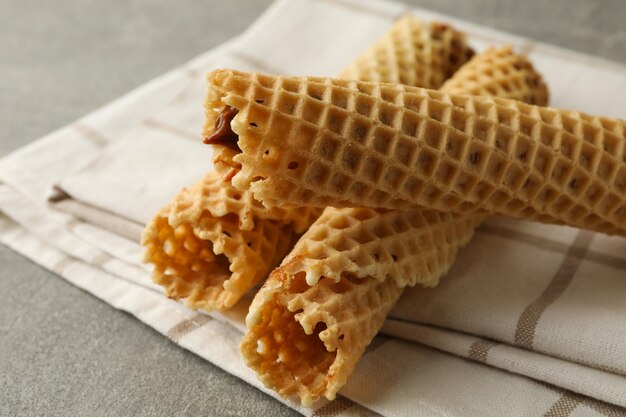 Foto tovagliolo con rotoli di wafer con latte condensato su grigio