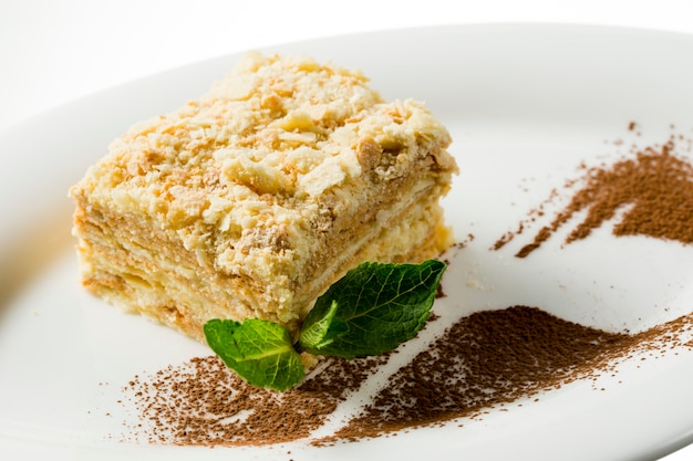 Napoleon cake with mint leaf on plate on white