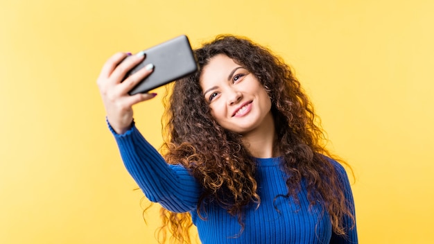 Narcissistic behavior. Social networking addiction. Young lady taking selfie on smartphone, smiling to camera.