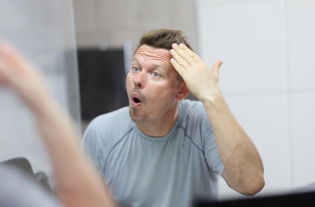 Narcissistic man in front of mirror does his hair