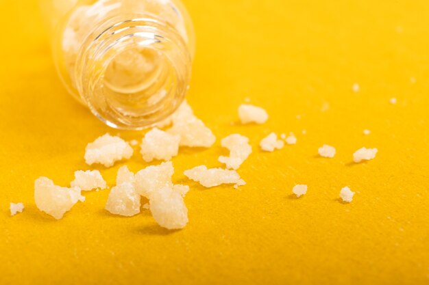 Narcotic salt crystals amphetamine on yellow background.