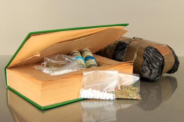 Narcotics in bookhiding place and packages on gray background