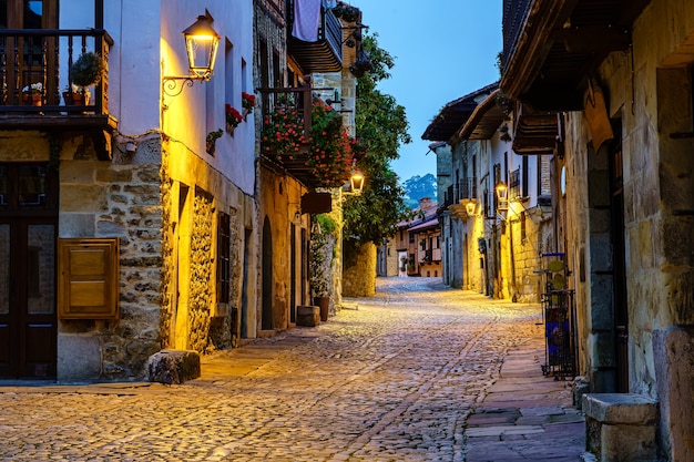 Narrow alley of old stone town with cobbled streets illuminated at night.