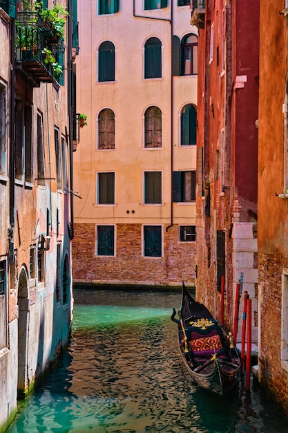 Canale stretto fra le vecchie case variopinte con la barca di gondola a venezia, italia