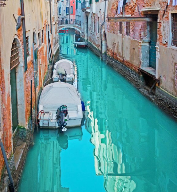 Narrow canal with boats in Venice Italy