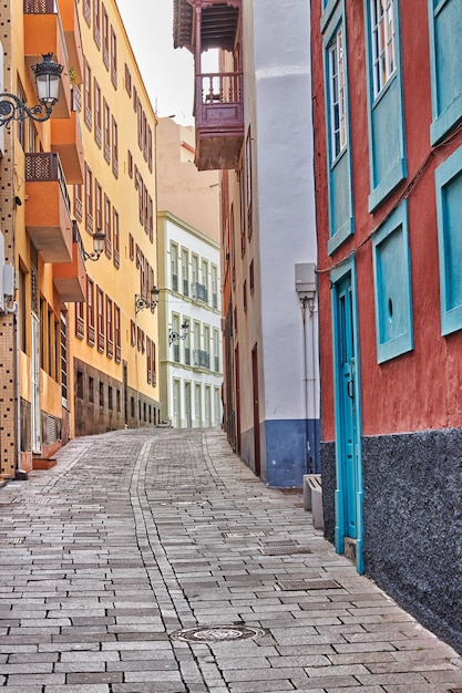 Narrow cobbled street or alley between colorful buildings in\
santa cruz de la palma bright and classical architecture in a small\
city or village beautiful houses or homes with a vintage\
design