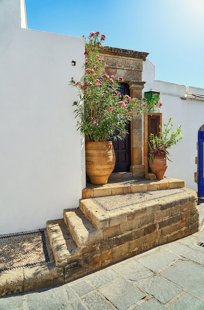 Narrow steep streets with houses white walls and blooming bushes and old stairs in old town Lindos