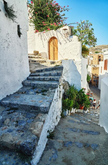 Narrow steep streets with houses white walls and blooming bushes and old stairs in old town Lindos