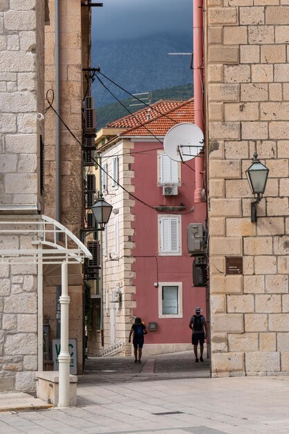 Narrow street in Makarska city Dalmatia Croatia Walking tourists Man and woman A popular tourist destination for summer holidays in Croatia