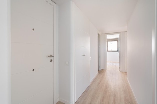 Narrow white corridor with doors and entrances to different rooms and premises and resting on a room