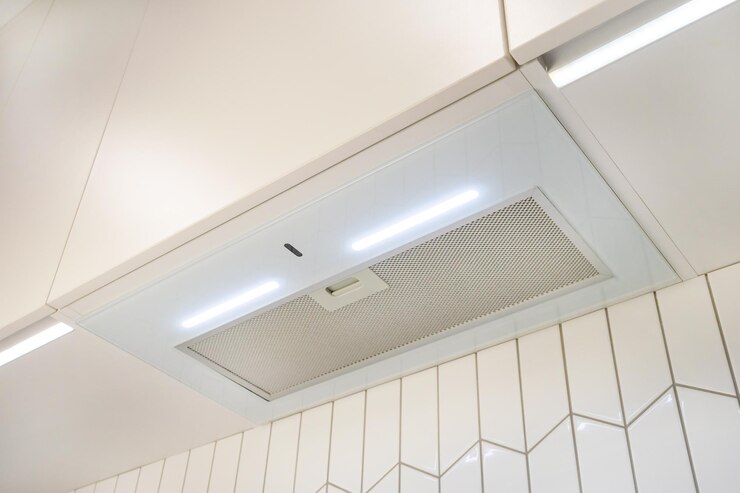 Photo a narrow white glossy hood over the hob with backlight against the background of white tiles.