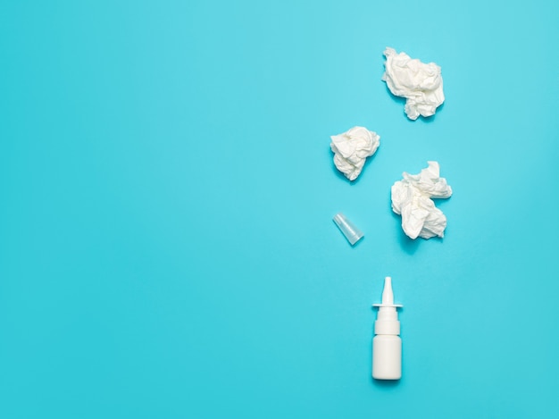 Nasal spray and crumpled wipes on a blue background.