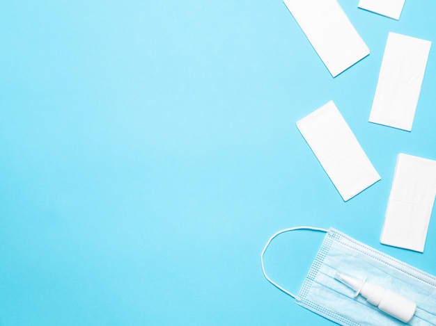 Nasal spray, mask and dry wipes on a blue background, top view.