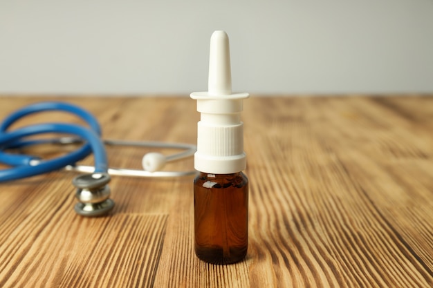 Nasal spray and stethoscope on wooden table