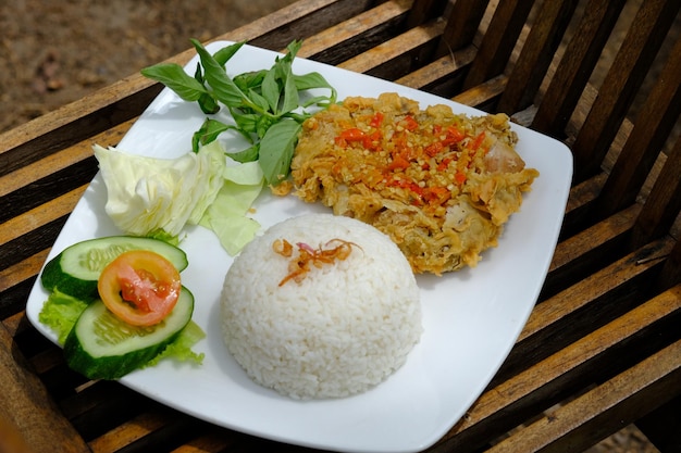 nasi ayam geprek. sambal lalap. is rijst met een bijgerecht van gebakken kip gemengd met chilisaus.