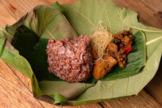 nasi berkat. brown rice, stir-fried vegetables, fried noodles, stewed tofu wrapped in teak leaf.