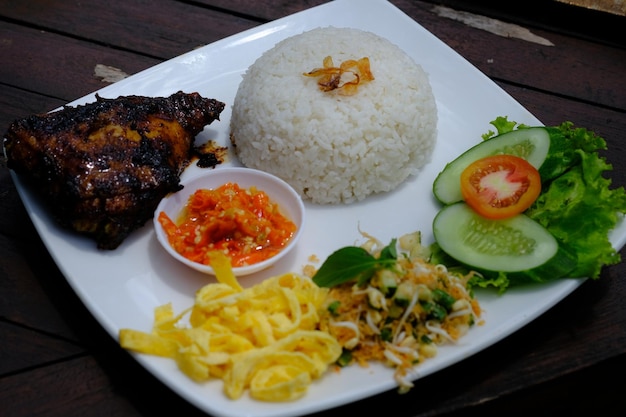 nasi campur is rice with ayam baker (grilled chicken), omelette, sambal (chili sauce), cucumber.