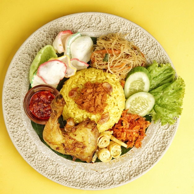 Photo nasi kuning jakarta, is a turmeric savory rice dish, served with ayam goreng and other side dishes.