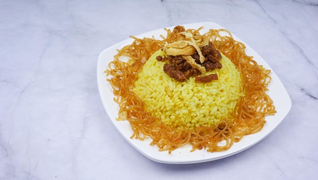 Foto nasi kuning of nasi kunyit in witte plaat populaire indonesische keuken met kokosmelk en kurkuma