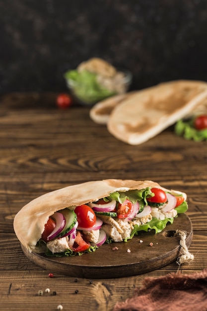 Nationaal Grieks fastfood pitabroodje met kip en verse groenten op een houten bord, donkere achtergrond, zijaanzicht met een kopie ruimte. Verticale oriëntatie.