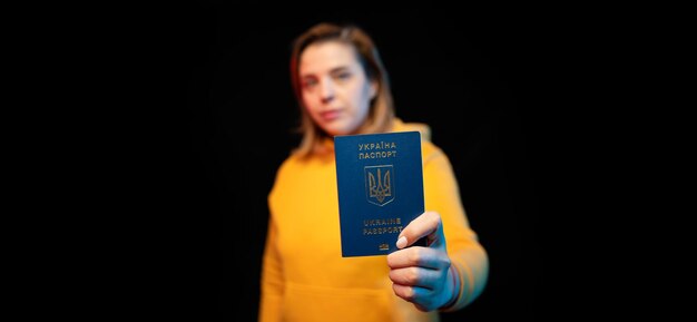 Nationaal paspoort van Oekraïne Mooi Oekraïens meisje met overheidspaspoort in haar handen op zwarte achtergrond