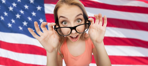 national, education and people concept - happy surprised young woman or teenage girl eyeglasses over american flag background