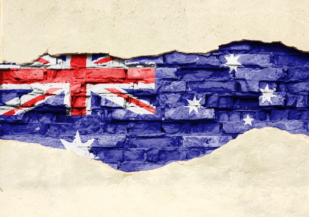 National flag of Australia on a brick background. Brick wall with partially destroyed plaster, background or texture.