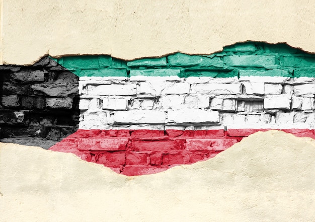 Photo national flag of kuwait on a brick background. brick wall with partially destroyed plaster, background or texture.