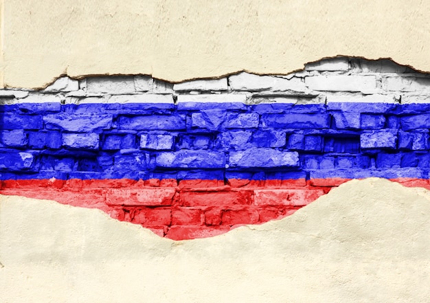 National flag of Russia on a brick background. Brick wall with partially destroyed plaster, background or texture.