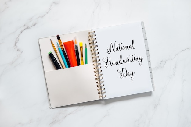 National handwriting day january hand lettering inscription text on paper notepad with pens and