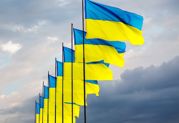 The national yellow and blue flags of Ukraine over the sky and clouds