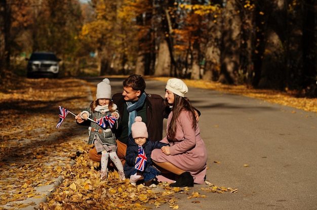 Nationale feestdag van het Verenigd Koninkrijk. Familie met Britse vlaggen in de herfstpark. Britsheid die het VK viert. Twee kinderen.