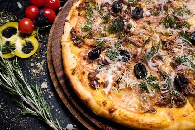 Nationale Italiaanse keuken. pizza bolognese met gehakt olijven en tomaten. verse groenten op de achtergrond