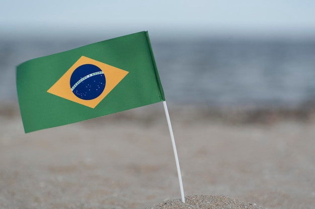 Nationale tafelvlag van Brazilië op zeeachtergrond Vlag van Brazilië op zandkust