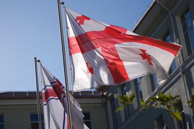 Nationale vlag van Georgië zwaaiend in de wind op blauwe hemelachtergrond internationale betrekkingen en