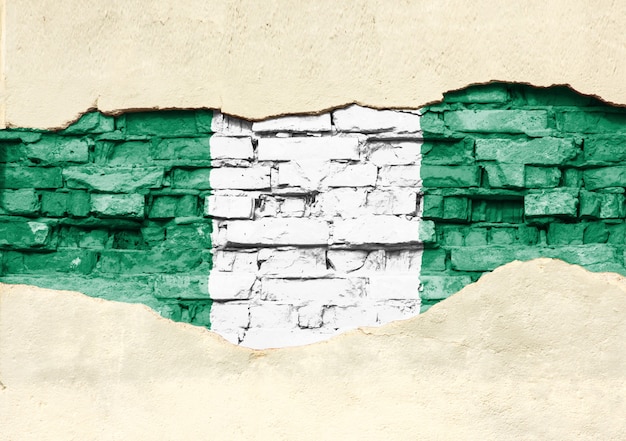 Nationale vlag van nigeria op een bakstenen achtergrond. bakstenen muur met gedeeltelijk vernietigde pleister, achtergrond of textuur.