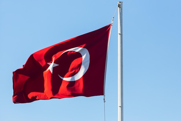 Nationale vlag van turkije op een vlaggenmast zwaaiend tegen een blauwe lucht