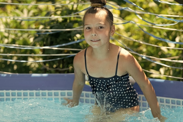 Natte jongen geniet van een zonnige zomerdag zwemmen in de vrije tijd van het buitenzwembad