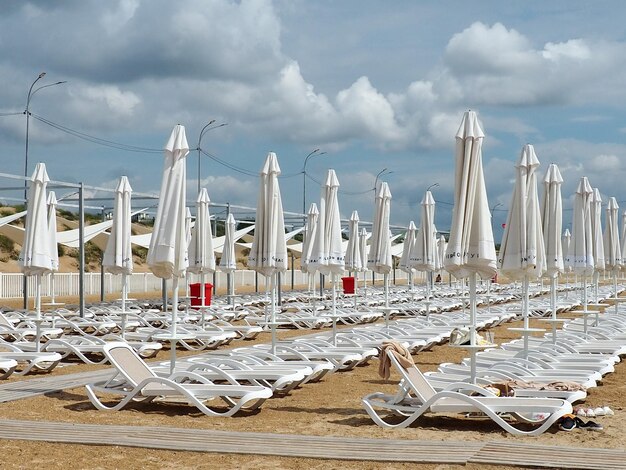 Natte ligbedden en parasols op het zeestrand tijdens zware regenstorm Opgerolde parasol op het strand tegen donkere bewolkte hemel Invasie van een tyfooncycloon of storm op zee of oceaan Strandseizoen