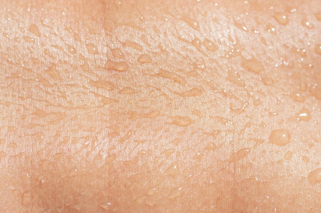 Natte vrouwelijke huidtextuur met vloeibare druppels close-up gelooid menselijk lichaam met waterdruppels