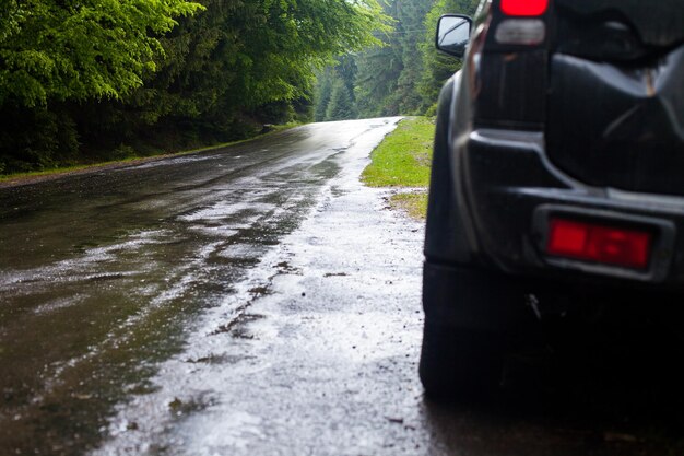 Natte weg na regen en auto die langs de weg in het bos staat