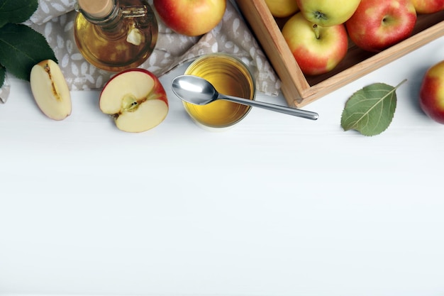 Natural apple vinegar and fresh fruits on white wooden table flat lay Space for text