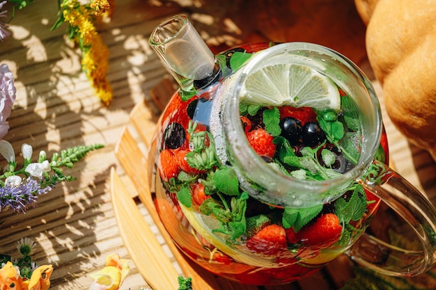 Natural aromatic fruit tea in a transparent teapot and in a cup\
among berries and flowers warming aromatic tea with a deep aroma of\
berries and wildflowers