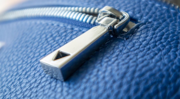 Natural or artificial leather texture. Fragment of a blue bag with a zipper and stitching. Zipper or clasp bag design element. Bovine skin texture with snake. Macro photo, selective focus.