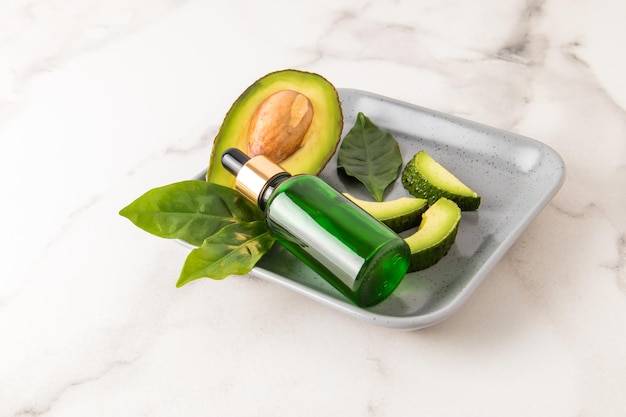 natural avocado oil in a cosmetic bottle with a pipette against the background of a ripe juicy fruit. deep moisturizing.