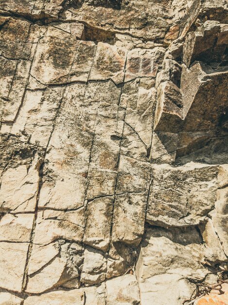 Natural background Closeup edged shabby cliff cracks Graybrown stone rock texture of mountains Vintage and faded matt style colour in tinted photo Concept of geolog mountaineering or hard work