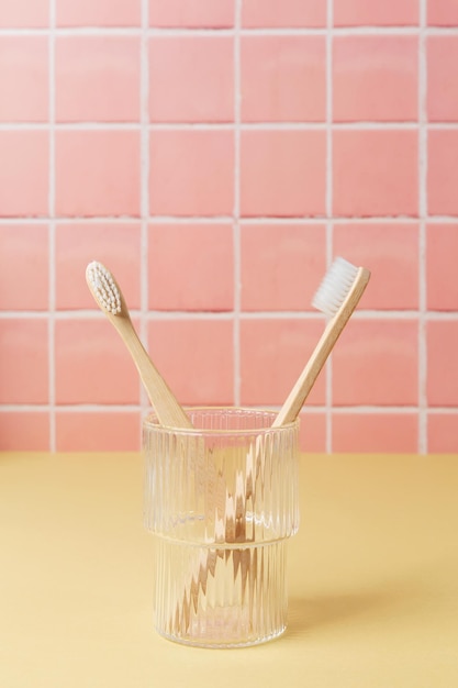 Natural bamboo eco friendly toothbrushes in a glass on table inside a bathroom wall tiles ceramic background