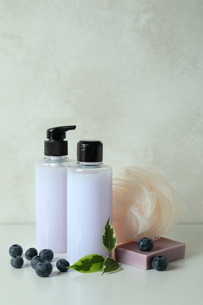 Natural bath cosmetics and blueberry against white textured background